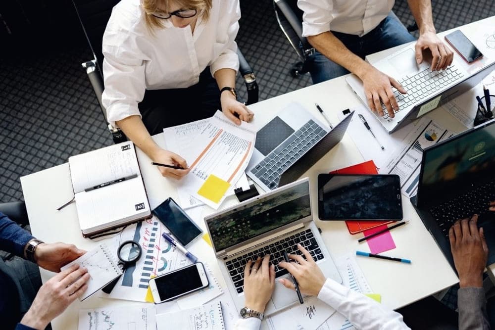 Overhead view of a diverse team collaborating around a table with laptops and documents